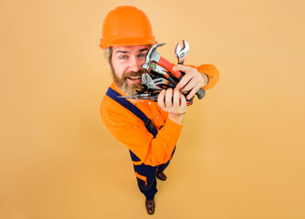 Smiling bearded man in protective hard hat with repair tools. Building industry. Male builder in safety helmet with different building tools. Construction worker with set of various hand work tools.