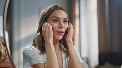Woman doing face lifting self massage at bathroom closeup. Lady looking mirror