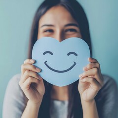 Embracing Positivity: A Woman Crafts a Joyful Smile on Blue Paper for World Mental Health Day, Symbolizing the Importance of Active Thinking and Psychological Well-being.