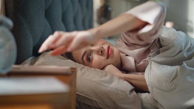 Smiling girl waking up in morning sunlight closeup. Happy woman checking phone