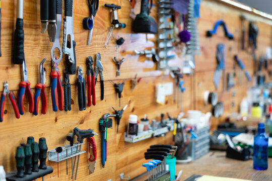 Variety of hand tools for bicycle repair neatly arranged on wooden wall in specialized professional bike workshop