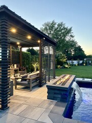 Stunning poolside gas fire pit filled with black glass compliments the in-ground, built in  pool at...