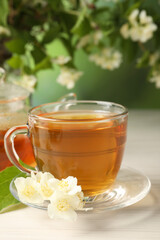Hot jasmine tea in cup and flowers on white wooden table
