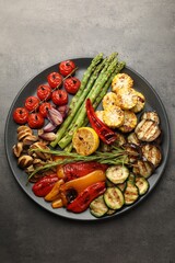 Delicious grilled vegetables on grey textured table, top view