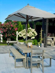 High-end outdoor living space, a backyard patio with pergola, outdoor rug,  tequila bar, dining set, couch, television, pool with waterfall, umbrella, fire pit and stunning grey patio. Modern vibe.