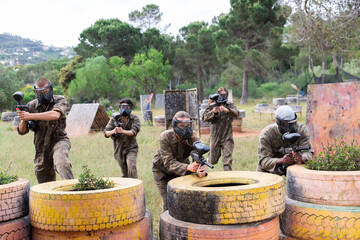Two active opposing teams with guns playing paintball against each other outdoors