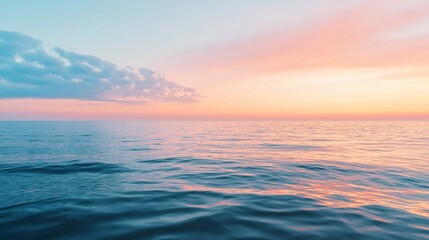 Obraz premium Gentle waves reflecting a pastel sunset over calm waters at the coastline.