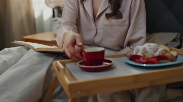 Breakfast woman hands reading novel at bed closeup. Model taking espresso cup