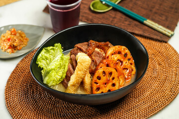 lotus root Cart Noodles pot with, lettuce leaf, drink and chopsticks served in pot isolated on napkin side view of japanese food