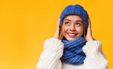 Breathe taking advertising. Super happy beautiful girl in blue knitted set looking up, holding her hat, pink background, empty space