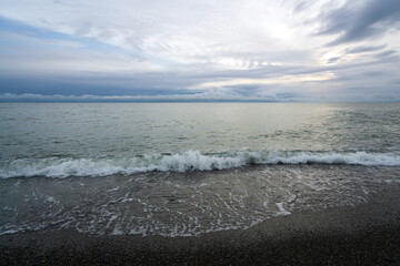 An incoming wave on the Black Sea coast against the sunset sky, Sochi, Krasnodar Territory, Russia