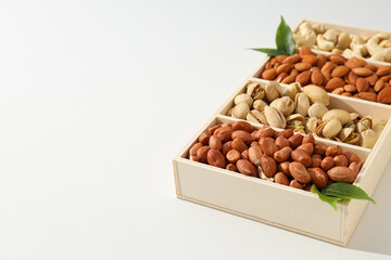 Wooden box with different nuts on a light background