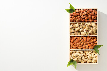 Wooden box with different nuts on a light background