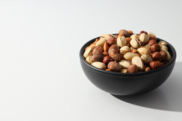 Assorted nuts in a black bowl on a white background