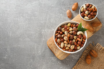 Assorted nuts in white bowls on a gray background