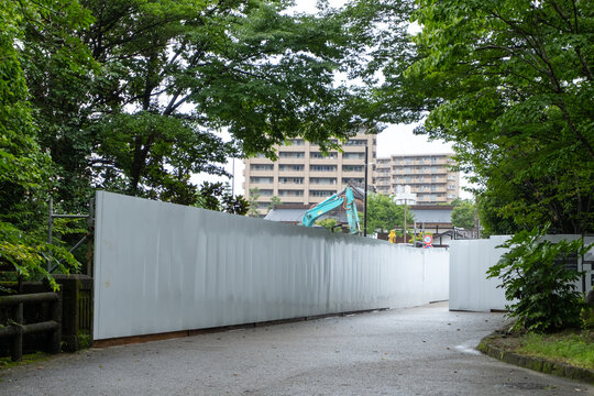 Long, empty blank white construction barriers or fence walls made up of several panels joined together, for temporary work sites in a park. Copy space for design.