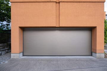 A closed, modern metallic garage roller door made of smooth, sleek material with a horizontal panel design, set against a concrete driveway.