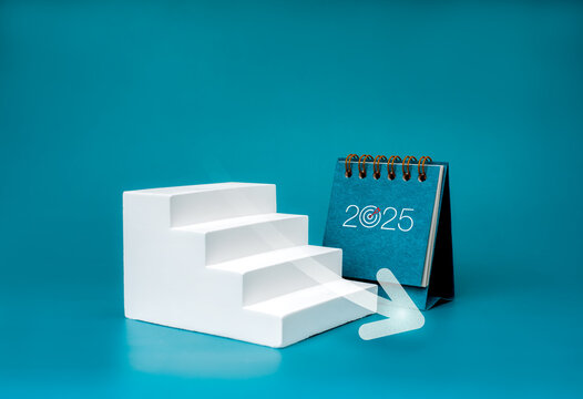 Happy new year 2025 background. 2025 numbers on desk calendar near arrow decrease on white geometric stairway, isolated on blue background, minimalist. Downtrend business, goal and success concept.