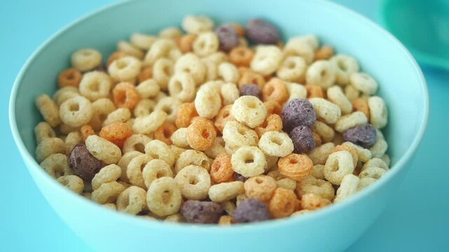 pouring milk into colorful cereal corn flakes in a bowl 