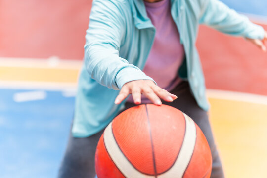 Active senior woman playing basketball in the urban outdoor basketball court