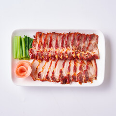 Roast pork and crispy pork with Chinese sausage on a white plate with side vegetables and pickled ginger.