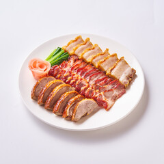 Roast pork and crispy pork with Chinese sausage on a white plate with side vegetables and pickled ginger.