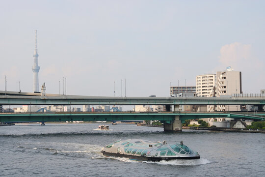 TOKYO, JAPAN - August 13, 2024: The futuristic pleasure boat Himiko on the River Sumida with a traditional yakatabune boat going under the Sumidagawa-Ohashi bridge. Tokyo Skytree is in the background.