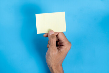 A hand holding a yellow card with a blank space