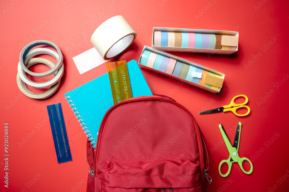 Poster a red backpack with a blue notebook and a green pair of scissors
