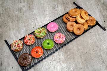 A tray of assorted mini donuts with sprinkles and frosting