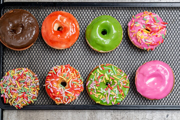 A tray of colorful mini donuts with sprinkles on top