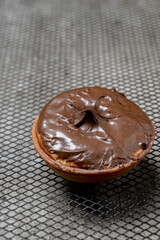 A chocolate mini donut sits on a metal mesh