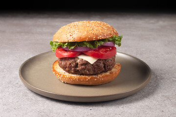 Homemade delicious hamburger with beef, onion, tomato, lettuce and cheese. Fresh burger close up on wooden rustic table with potato fries. Cheeseburger. Burger.