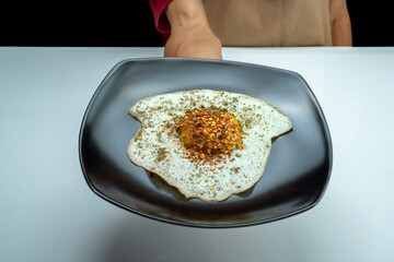 A plate of sunny side up egg food with a black plate and a white plate