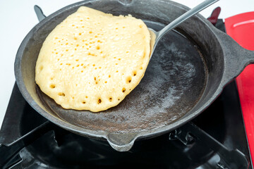 A pancake is being cooked on a red stove top