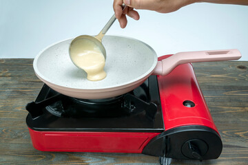 A person is cooking food in a pan on a stove