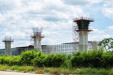 Concrete pillars rising with scaffolding and formwork at a bridge construction site, capturing the...