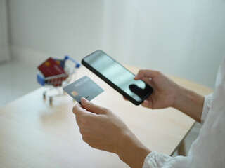 Woman sitting shopping online, using smartphone, holding credit