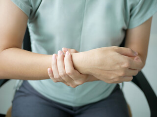 A young businesswoman has severe pain in her wrist. She has numbness. She massages her arm by...