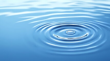 A single drop of water creating ripples on a calm blue surface.