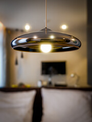 A simple semicircular shaped pendant lamp hangs on the ceiling close up.
