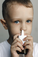 A sick child with a runny nose uses nasal spray to relieve congestion.Perfect for health, illness, and care themes. High-quality image of respiratory relief and treatment for cold and allergy symptoms