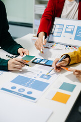 Close up view of UI developer team brainstorming on their project with laptop, smartphone and...