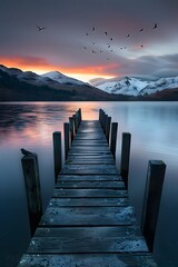 Fototapeta premium Sunrise over the lake. A jetty on the waters of lake garw, mountains in the background, 