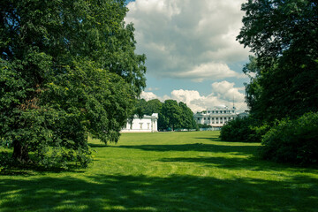 A large white house sits in front of a large green field