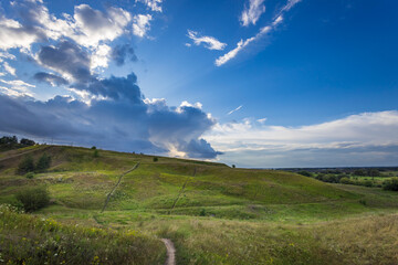 A tranquil moment unfolds as the sun casts golden rays over rolling green hills, while dramatic...
