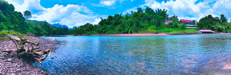 A serene river flowing through a lush tropical forest, Kanchanaburi, Thailand.