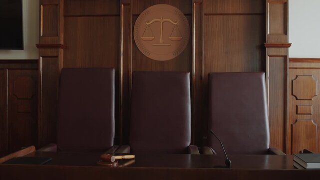 No people shot of three leather chairs and wooden desk with gavel, microphone, folder, books in courtroom
