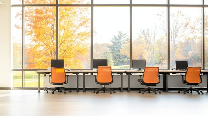 Modern office workspace with orange chairs and large windows showcasing autumn trees. Bright and inviting atmosphere for productivity.