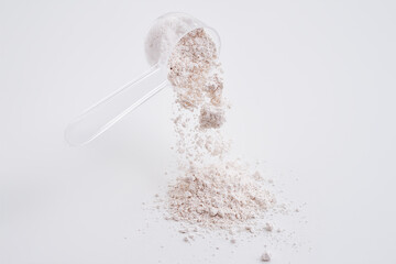 Powdered calcium citrate poured from a measured cup. White background isolated high speed freeze...
